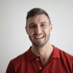 A cheerful man smiling broadly against a plain white background.